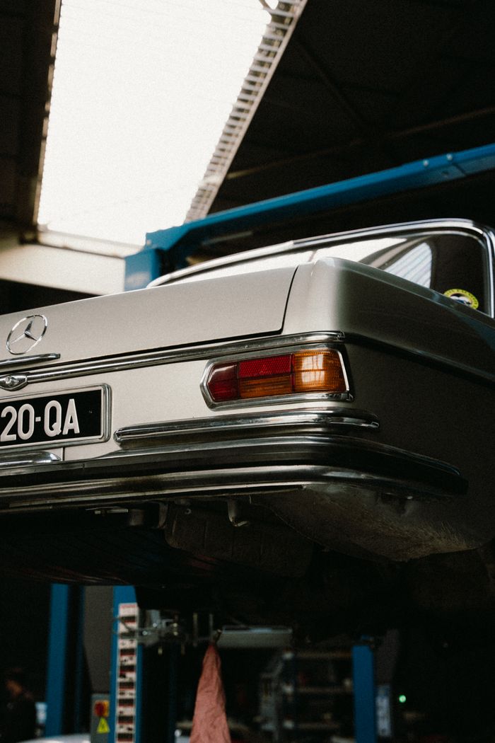 Vintage Mercedes on a car lift in a professional auto repair garage.