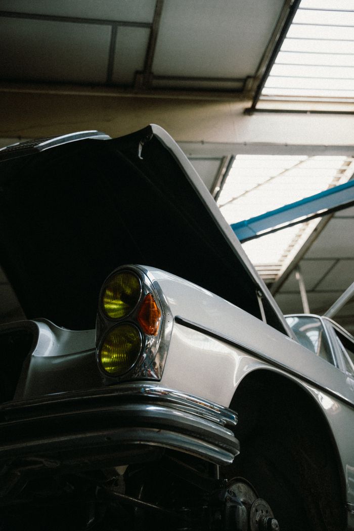 about-us Vintage car with open hood in a garage, showcasing retro design and detailed craftsmanship.